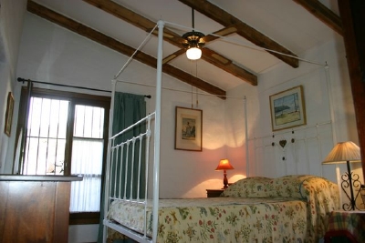 En suite bedroom emphasising height of room and wood beam ceiling.