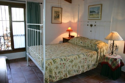 Large four poster cast-iron bed with high beamed ceiling.