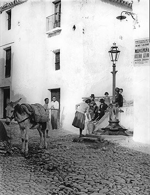 Auf einem Foto in den 60er Jahren getroffen, sammelt eine Frau Wasser an einem Brunnen mit einem Ton Aufnahme und ein Maultier zu helfen, sie tragen ihn nach Hause.