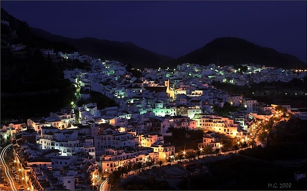 A beautiful night shot of Frigiliana. A beautiful night shot of a glowing Frigiliana with the dark silhouette of the mountains in the background.